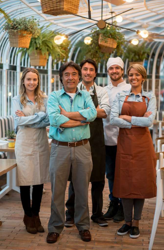 Happy group of people working at a restaurant and smiling at the camera